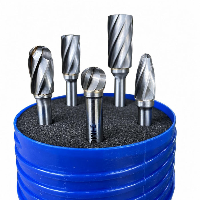 Five metallic rotary burr bits arranged in a blue plastic holder filled with dark grinding media, photographed on a white background.